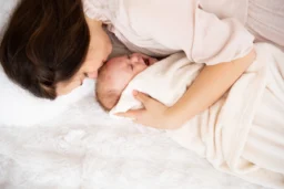 Anya és újszülött baba puha takaróban, meghitt pillanat.